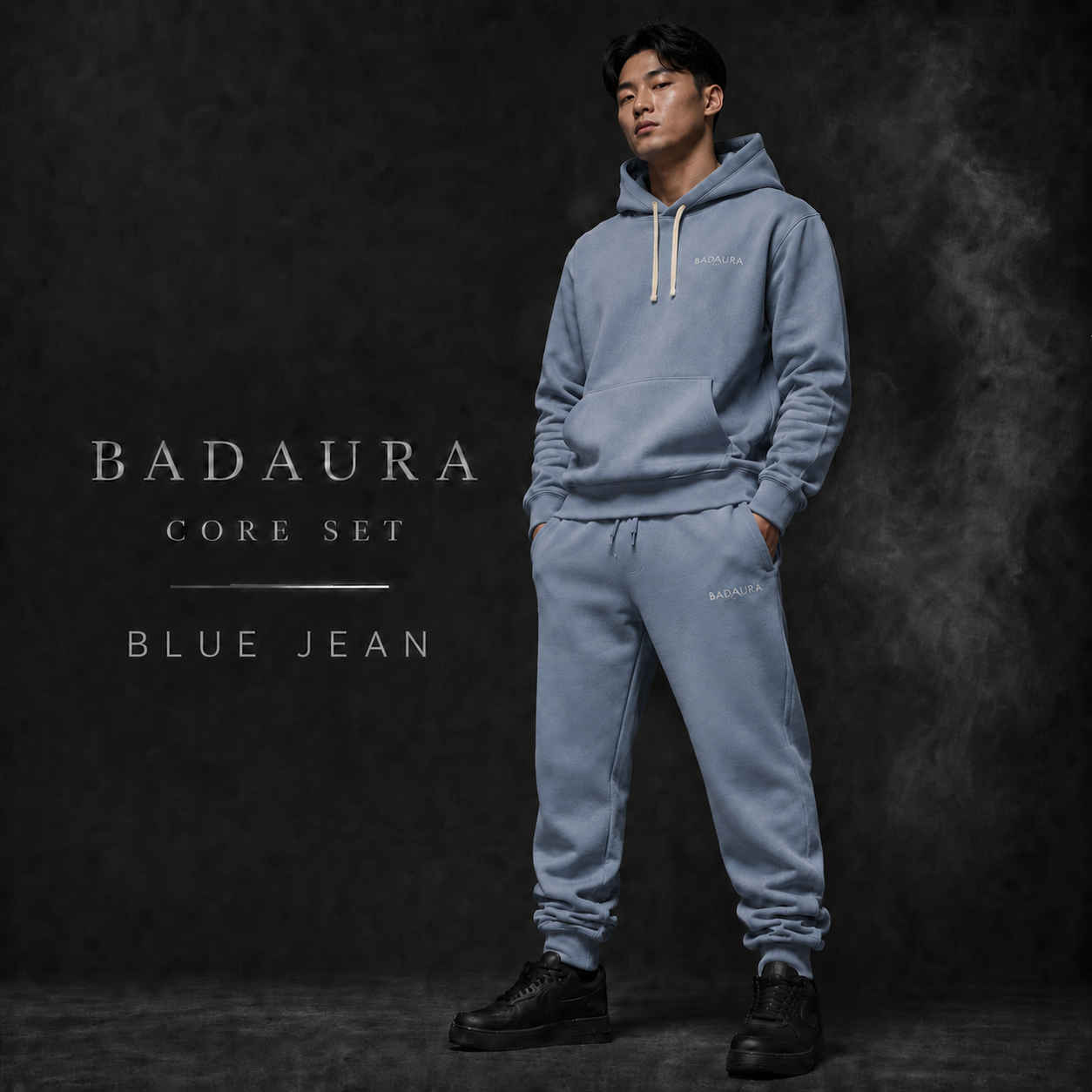Person wearing a blue hoodie and pants set with 'Badaura' branding on a dark background.