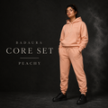 Person wearing a peach tracksuit with 'Badaura Core Set' text on a dark background